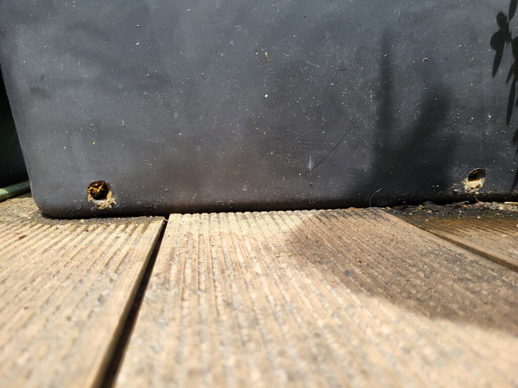 Drainage holes drilled near the bottom of a large rooftop garden container
